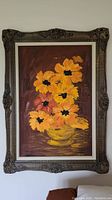 Full view of the framed floral painting showing the vibrant orange and yellow flowers in a yellow vase with ornate dark wood frame.