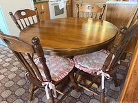 Round wooden kitchen table with four matching chairs showing seat cushions