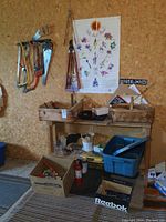 View of tools hanging on wall including saws, hand saws, and display of wooden and basket boxes containing miscellaneous items on a wooden shelf. Various items on floor including cardboard boxes and fire extinguisher.