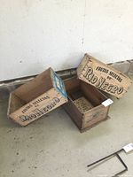 Three vintage wooden fruit crates marked with 'Frutas Selectas de Rio Negro' and 'Peras de Rio Negro Valle Medio' on a concrete floor.