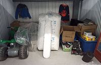 Storage unit overview showing green ATV, foam peanuts, light diffuser, jacket, jersey, bins and flat panels