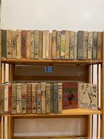 Shelf view of 37 vintage Horatio Alger Jr. hardcover books, with painted cloth spines and black illustrations.