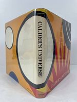 Front and side view of Calder's Universe art book with colorful dust jacket, showing title and author on spine.