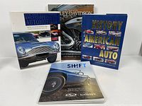 Four car collector books arranged on a white surface showing cover images with classic cars and motorcycles, titles visible.
