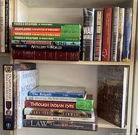 Photo of 22 assorted military history books on two shelves, including titles on artillery, warplanes, World War I and II, Napoleonic wars, Soviet airborne, and other military topics.