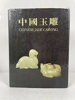 Front view of the Chinese Jade Carving book by The Urban Council, showing the black dust jacket with title in Chinese and English and images of two jade carvings.