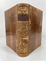 Front view of leather bound book spine with gold embossed detailing and author names.