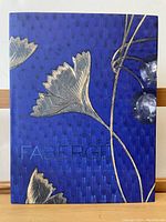 Front view of Faberge book showing decorative blue cover with gold floral designs and embossed title