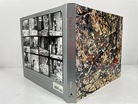 Front and back view of the Jackson Pollock hardcover art book with dust jacket showing Pollock's signature abstract paint splatter art on front and grid of vintage studio photos on back.