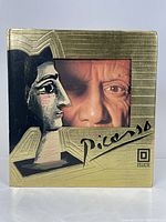 Front cover of the Picasso art book with gold embossed design and images of Picasso's artwork and face.