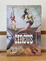 Front cover of 'The Circus 1870's - 1950's' hardcover book showing vintage circus artwork with trapeze artists and performing animals.