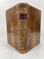 Full view of spine and partial front/back leather cover showing decorative gold tooling and wear.