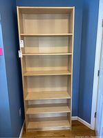 Front view of the wooden bookcase showing six shelves and light wood finish.