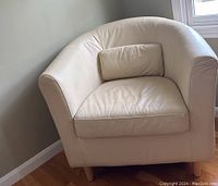 Front and side view of beige leather-like club chair with lumbar pillow showing armrests, seat cushion, and wooden legs.