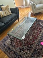 Full view of rectangular glass coffee table on rug between sofas