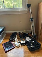 Full lot showing assorted electronics including tablet devices, smartphones, keyboard, chargers, surge protector, electric shaver, and tripod standing.