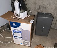 GE dehumidifier beside its original box with Air Innovations humidifier on top