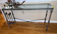 Full view of rectangular glass top console table with metal frame and decorative legs.