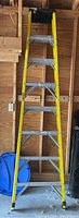Full view of Husky fiberglass ladder standing upright showing overall condition, yellow fiberglass sides, metal steps, in garage setting.