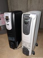Two Kenwood oil-filled heaters side by side, one black and one white, showing front digital control panels and fins.