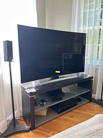 55-inch Samsung curved TV on stand flanked by speakers