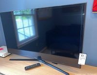 Front view of 40 inch TV on stand with remote on table