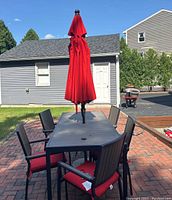 Wide shot of table with umbrella and six chairs on brick patio