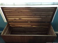 Open cedar chest showing the interior lined with cedar wood planks and metal hinges on the lid.