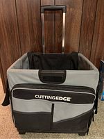 Front view of the Cutting Edge multi-purpose organizer cart showing the gray and black fabric exterior with front pockets and the brand logo.
