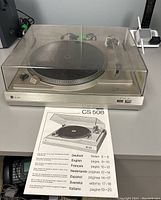 Full top view of Dual CS 508 turntable with clear dust cover and instruction manual placed in front.