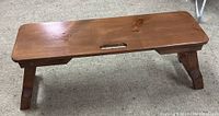 Folding pine bench fully opened and standing on carpeted floor