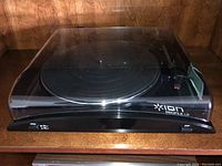 Front view of black ION Profile LP USB turntable with closed dust cover, showing the platter and control buttons on the front panel.