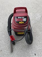 Front view of red Shop-Vac Hang Up Mini vacuum with hose and nozzle attached, showing labeling and overall condition.