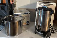 Stock pot and West Bend coffeemaker with original boxes in background on countertop.