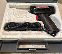 Weller Expert soldering tool in molded styrofoam case inside a plastic carrying case, showing tool, cord, and shape of possible accessories.