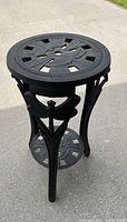 Full view of the wrought iron plant stand showing the top and lower shelf along with the three legs.