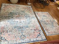 Both rugs shown laid on wooden floor, showing size difference and matching patterns.