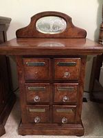 Front view of one wood nightstand showing six drawers with brass plates and crystal knobs, shaped top backsplash with etched glass design.