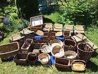 Full collection of assorted baskets on grass and blue cloth with natural and dark wicker tones.