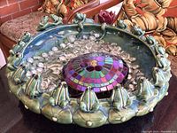 Top view of ceramic bird bath showing frog figures on rim, glass pebbles, and mosaic-covered rock centerpiece.