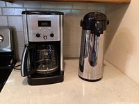 Cuisinart coffee maker and stainless steel insulated carafe placed on a countertop.