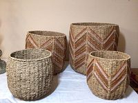 Four baskets grouped on table showing three with yarn herringbone pattern and one plain woven basket