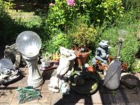 Wide view of garden decor items including glass sphere on pedestal, multiple frog statues, planters, and solar garden light