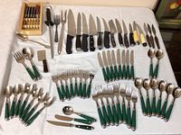 Full layout of green handled Oneida flatware including forks, knives, spoons, plus various kitchen knives and forks.