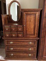 Front view of highboy dresser showing top six small drawers with brass plates and crystal knobs, right cabinet, and three lower drawers