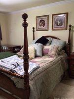 Full view of wooden queen bed frame with brass-accented spindles, mattress with bedding, and framed artwork overhead.