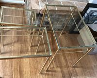 Set of 3 nesting tables showing rectangular clear glass tops and gold bamboo-patterned brass legs from an overhead angle.