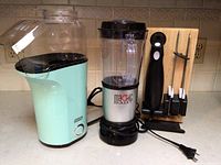 Blue Dash popcorn maker, Magic Bullet blender and Kitchen HQ electric cutlery set shown together on a countertop.