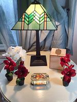 Photo showing lamp, tissue box holder, jewelry box, and artificial flowers arranged on table.