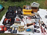 Wide view of all tools and hardware laid out on a white sheet outdoors to display entire lot